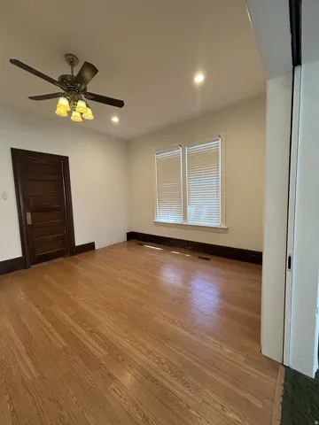 Room featuring wood-finish flooring, white walls, and dark baseboards