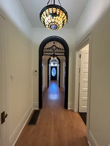 Hallway featuring wood-finish flooring, white baseboards, and light-colored walls