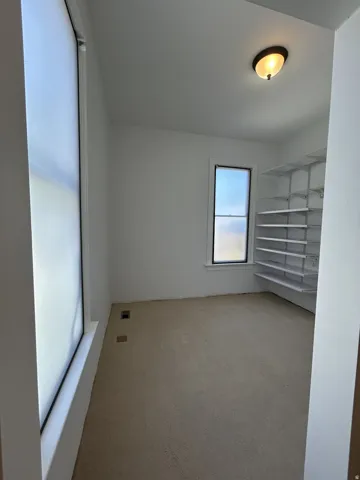 Room featuring light-colored carpeting, white walls, and two windows