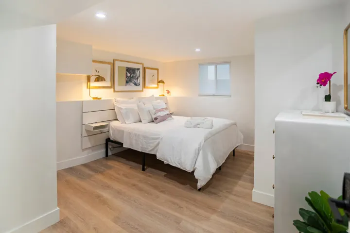 Bedroom featuring light wood-finish flooring, recessed lighting, a window with a roller shade, and built-in wall shelving