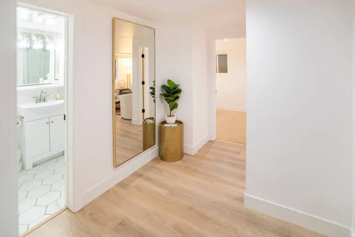 Light wood-finish flooring extending through a clean white hallway