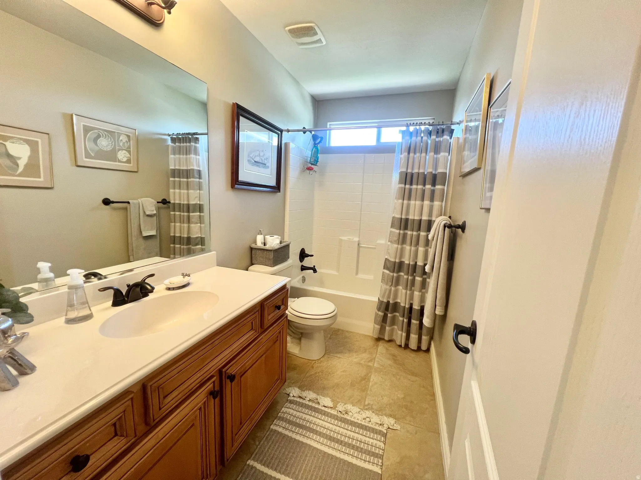 Bathroom featuring a warm wood vanity with an integrated sink, broad wall mirror, and a full bathtub with a shower