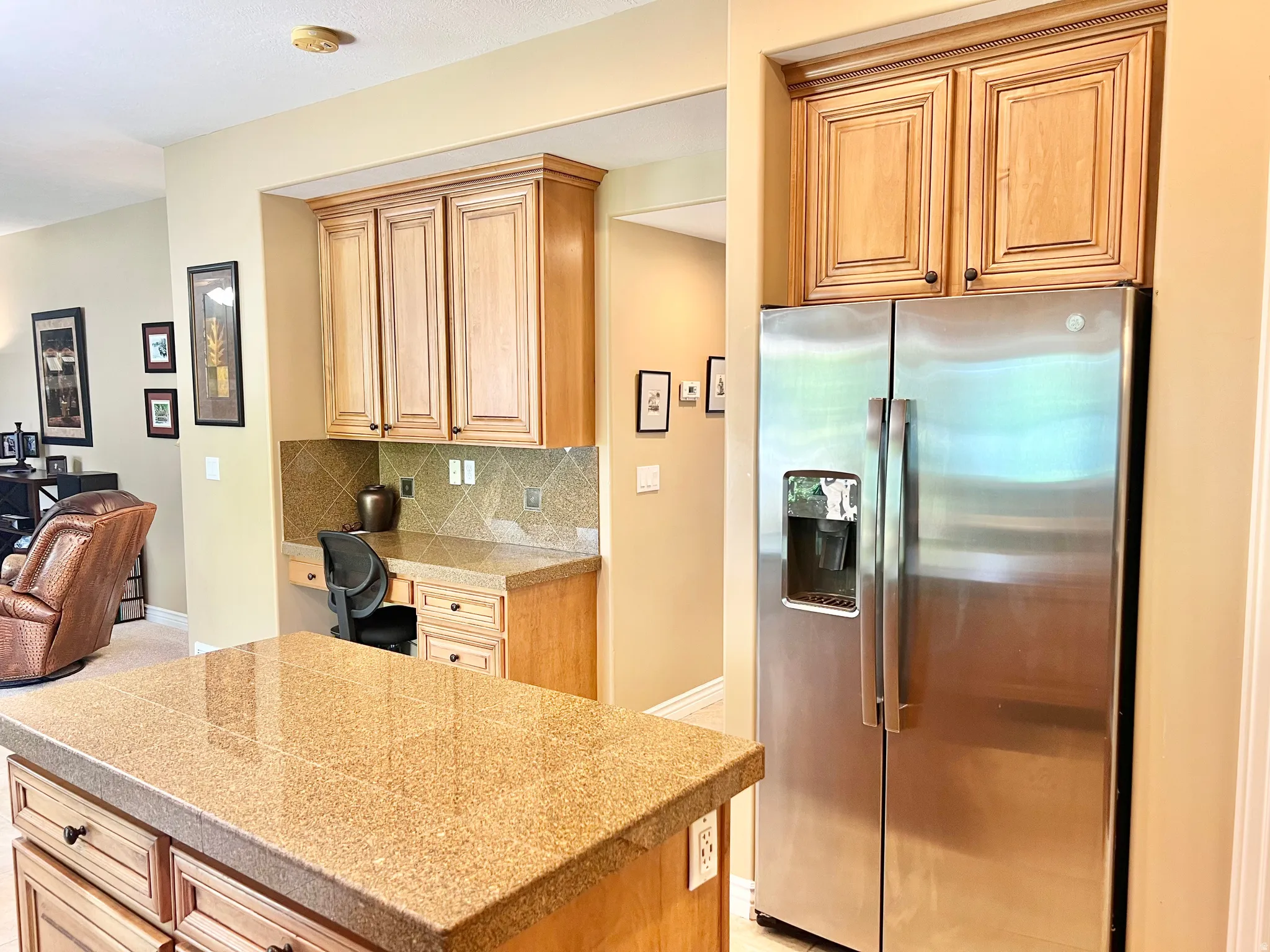 Kitchen island with a speckled granite countertop, integrated desk area, and wood-finish cabinetry