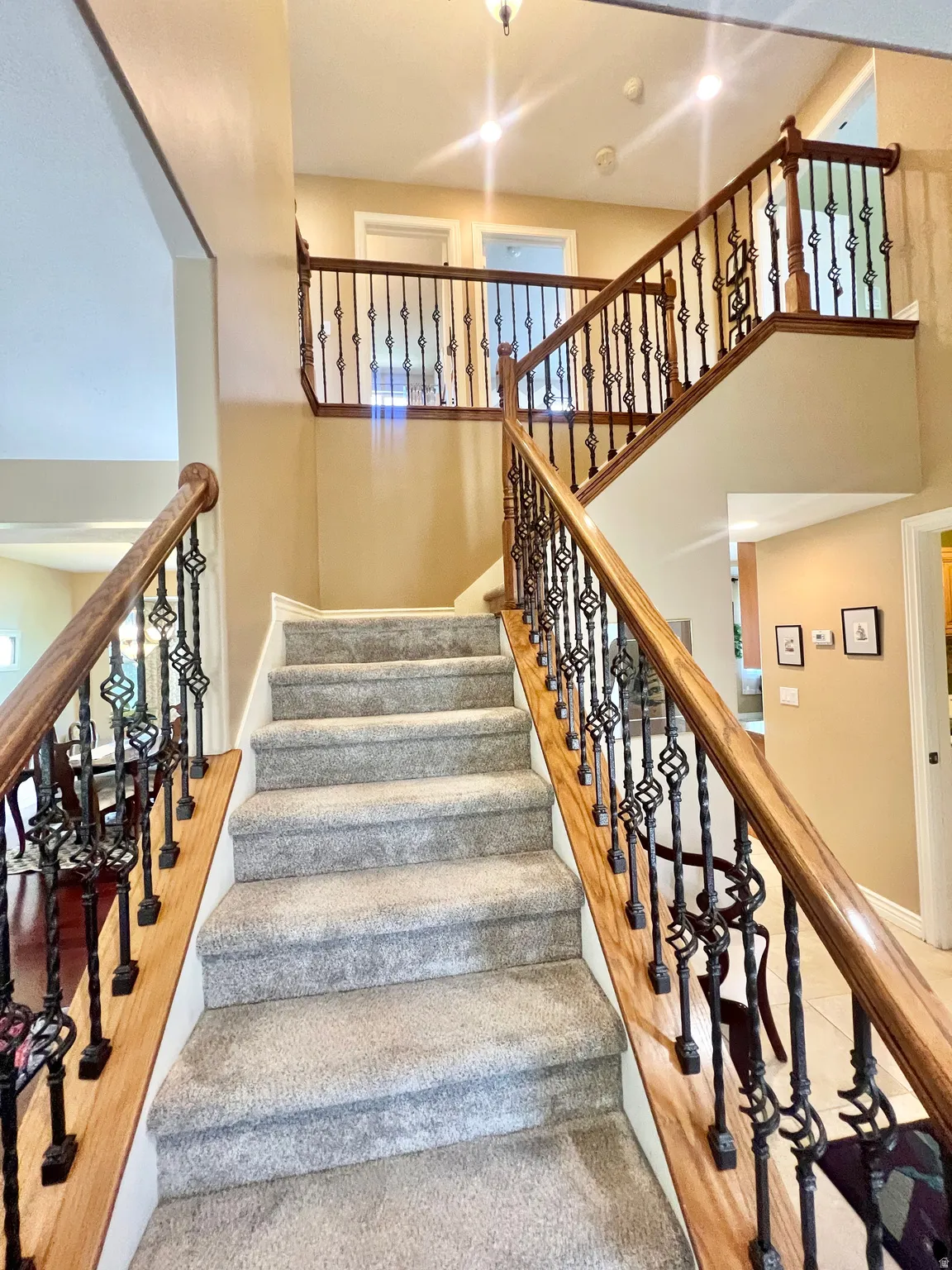 Grand staircase featuring decorative wrought iron balusters and wood handrails