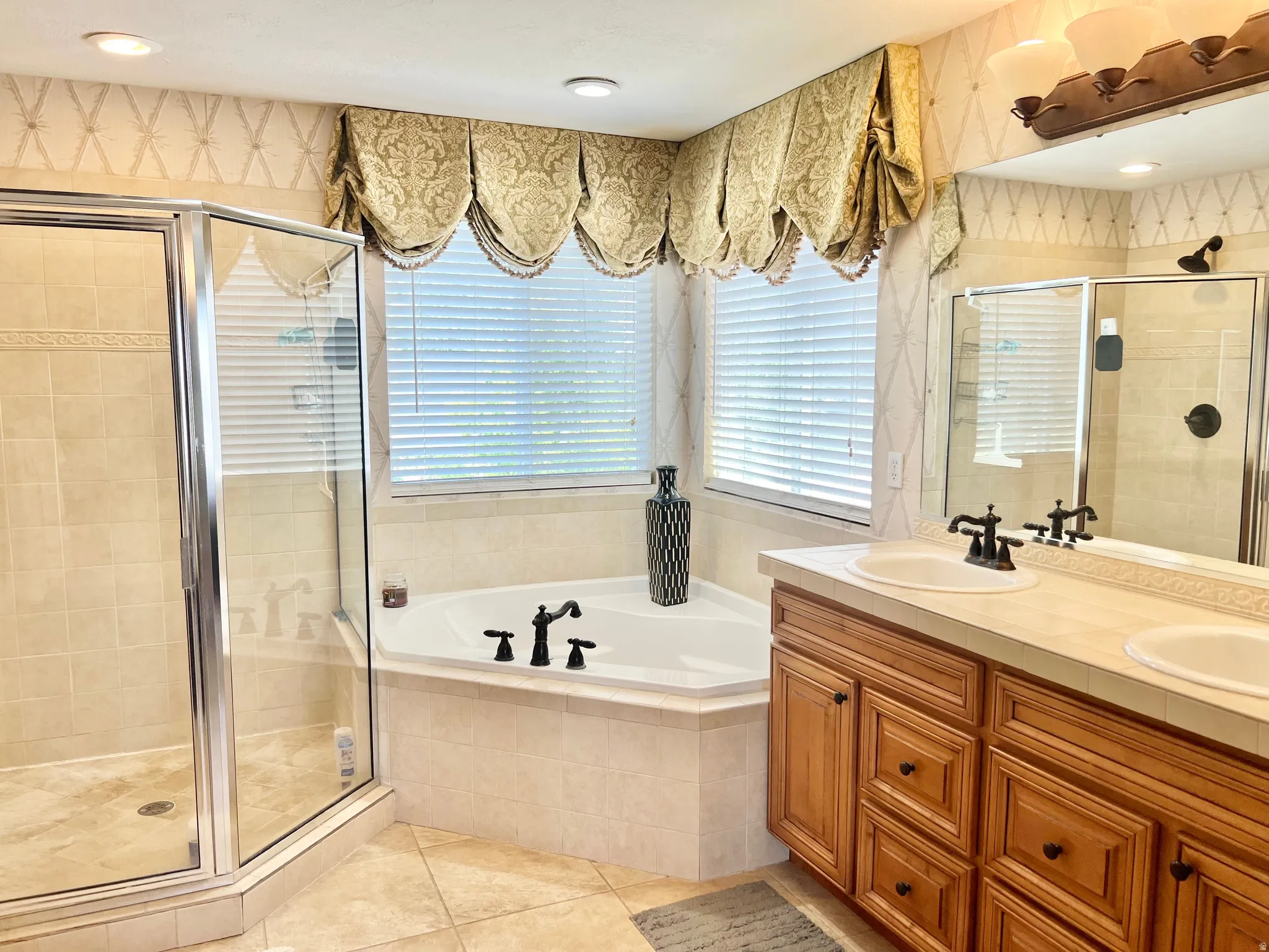 Corner soaking tub with a tiled surround, framed by a window with custom valances