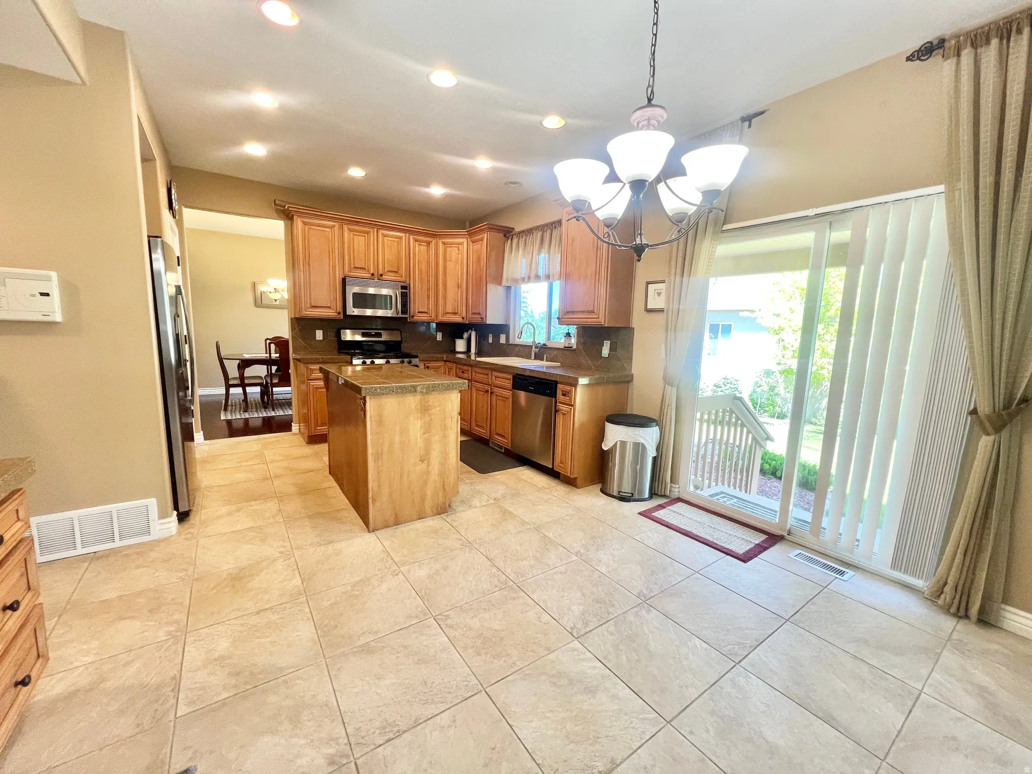 Kitchen featuring wood cabinetry, stainless steel appliances, and a central island with a stone countertop