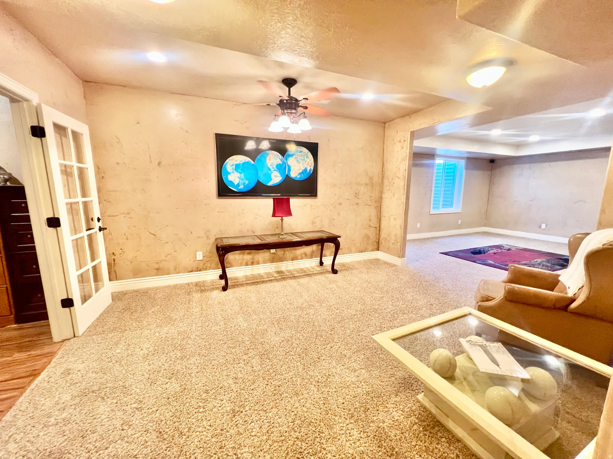 Spacious room featuring textured walls, recessed lighting, and soft carpet flooring