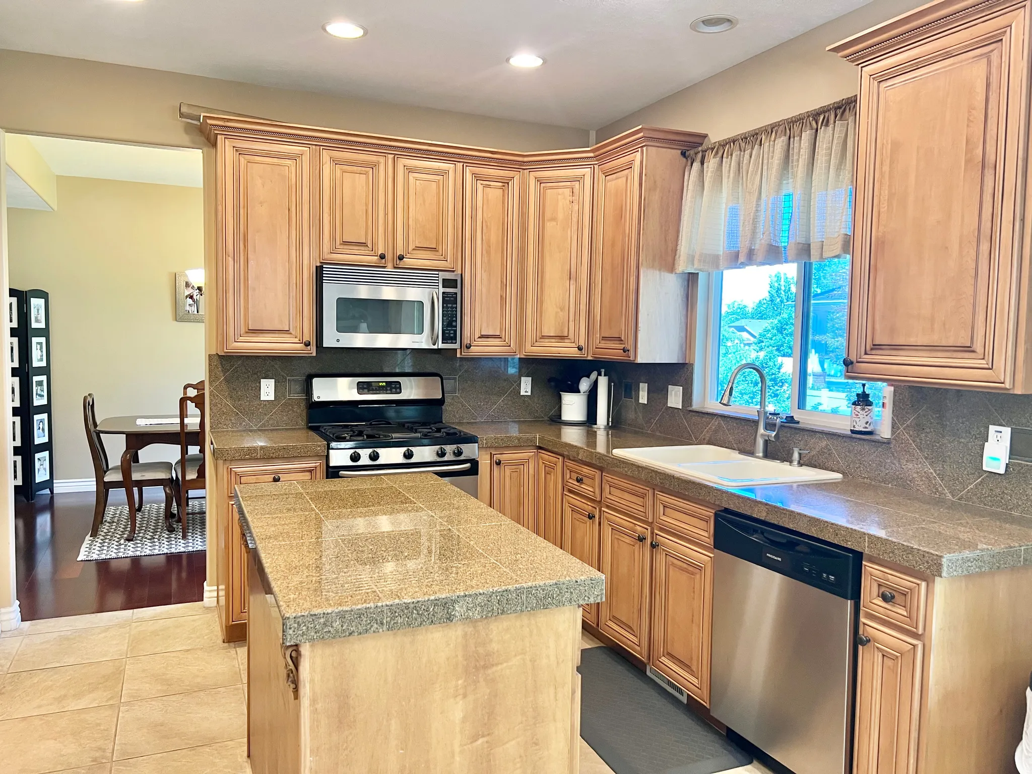 Kitchen featuring recessed lighting, honey-toned cabinetry with crown molding, stainless steel appliances, and a tiled island
