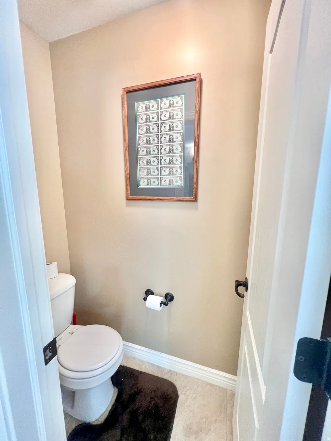 Compact water closet featuring neutral wall paint and light-toned floor tile