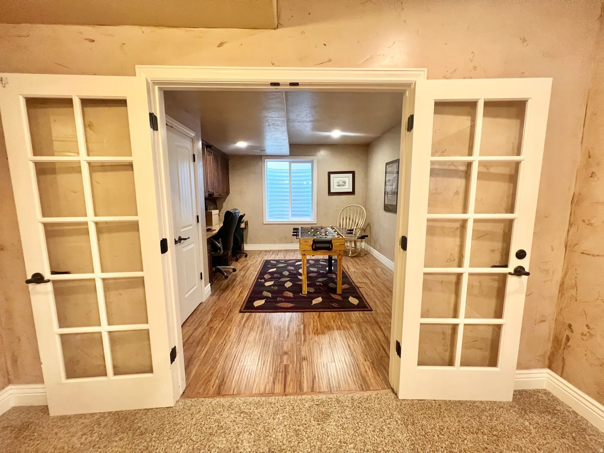 French doors opening to a versatile room featuring wood-finish flooring, recessed lighting, and a window with white shutters