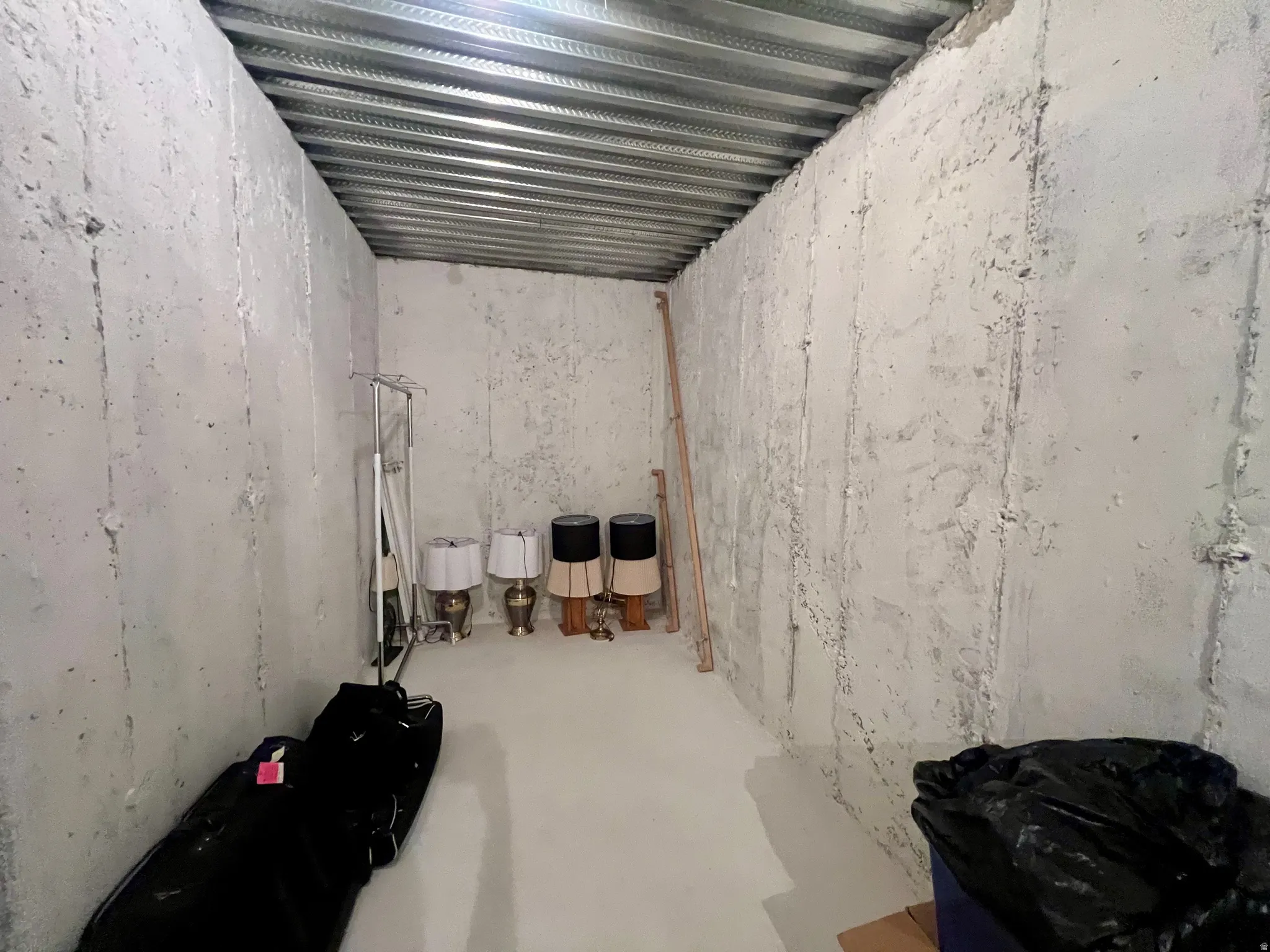 Unfinished room featuring concrete walls and a metal ceiling