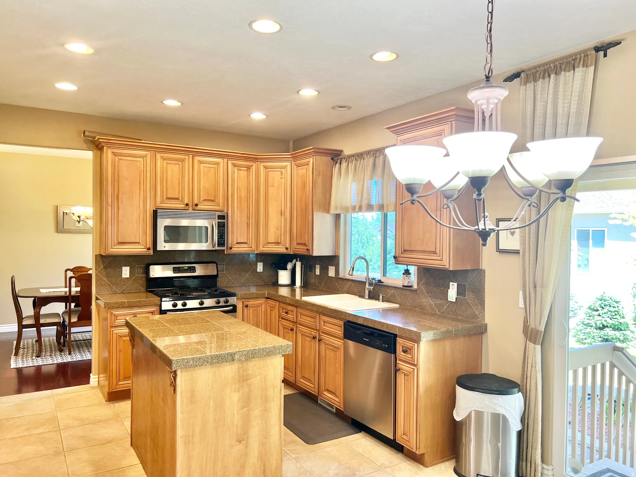 Kitchen featuring tile flooring, wood-finish cabinetry, tile countertops, and a tile backsplash