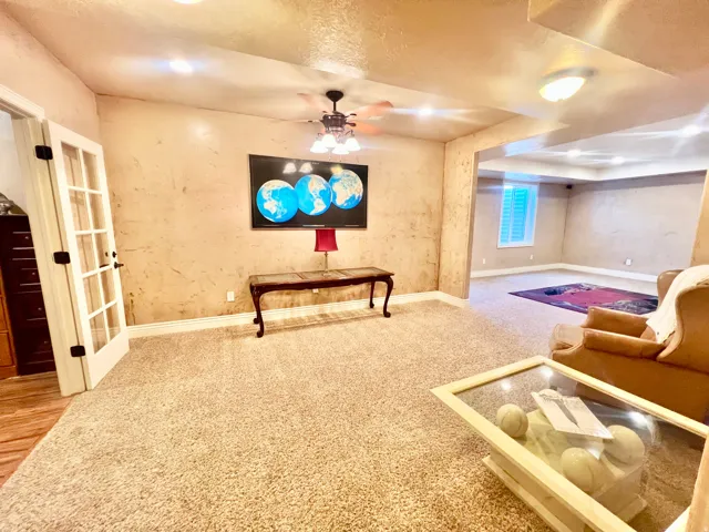 Spacious room featuring textured walls, recessed lighting, and soft carpet flooring