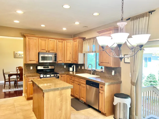 Kitchen featuring tile flooring, wood-finish cabinetry, tile countertops, and a tile backsplash
