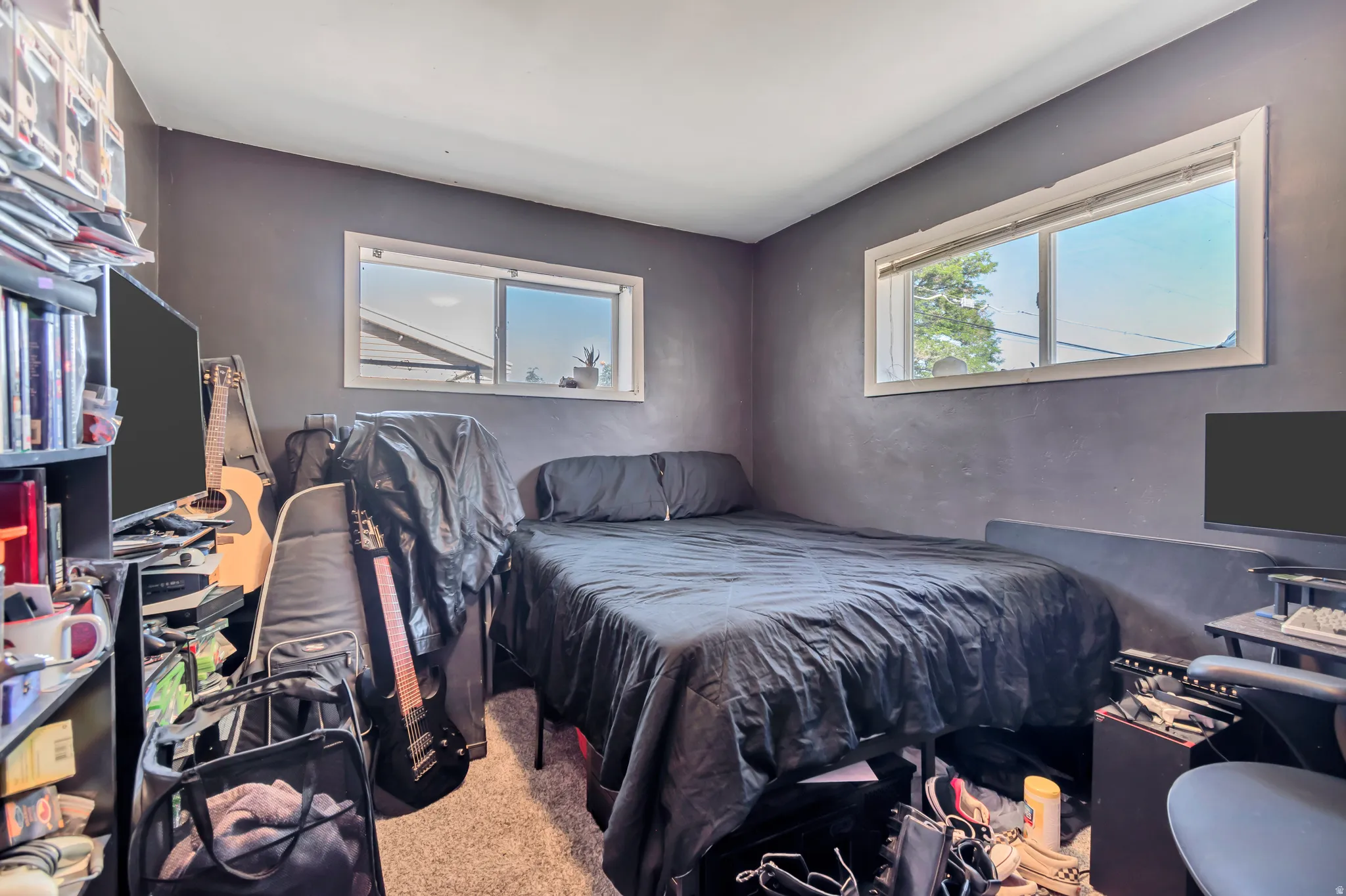 Room featuring two windows with white trim, gray textured walls, and light-colored carpeting