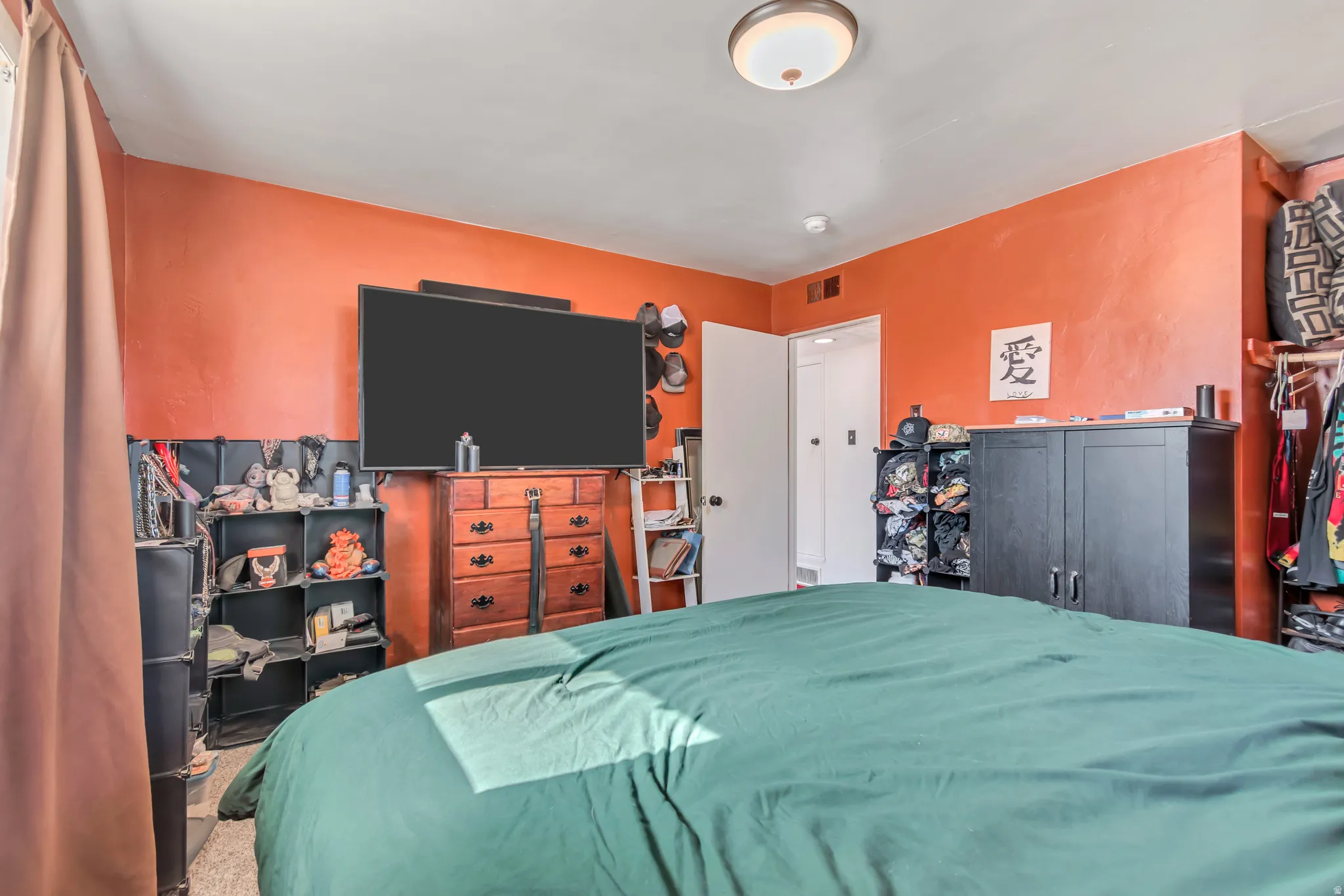 Bedroom featuring vibrant orange walls, a built-in closet with shelving, and a ceiling-mounted light fixture