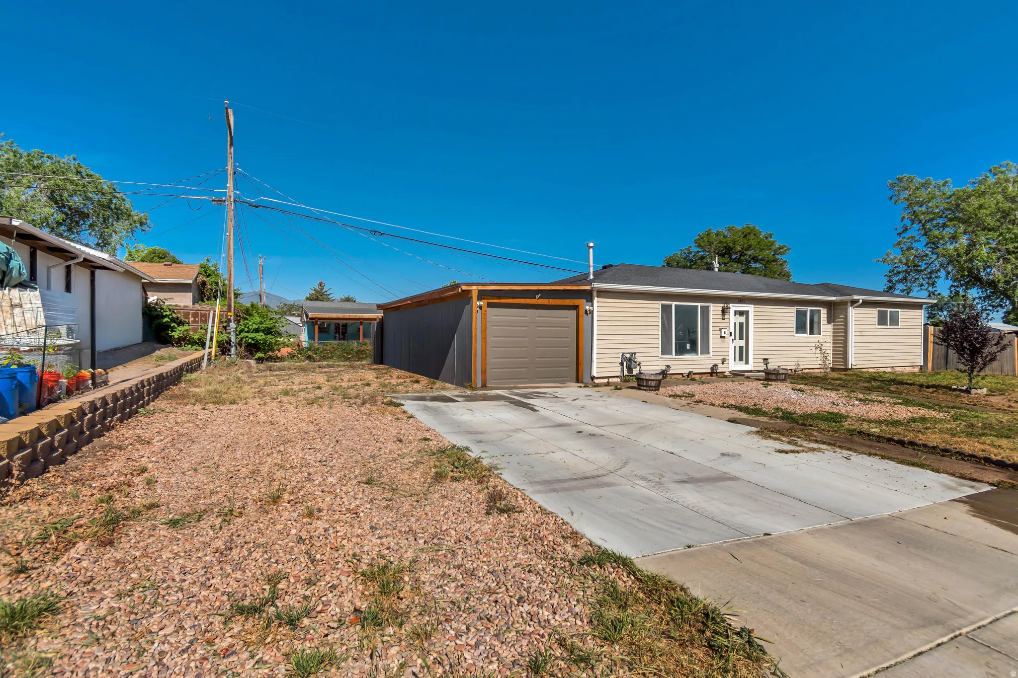 Exterior featuring neutral-toned horizontal siding, a dark asphalt shingle roof, a single-car garage with a brown door, and a concrete driveway