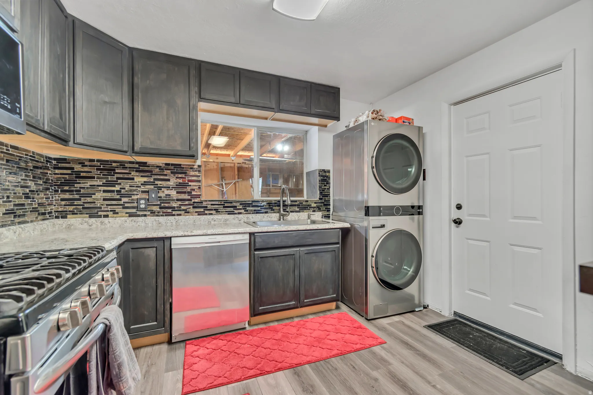 Kitchen featuring dark wood-finish cabinetry, mosaic tile backsplash, and light-toned countertops
