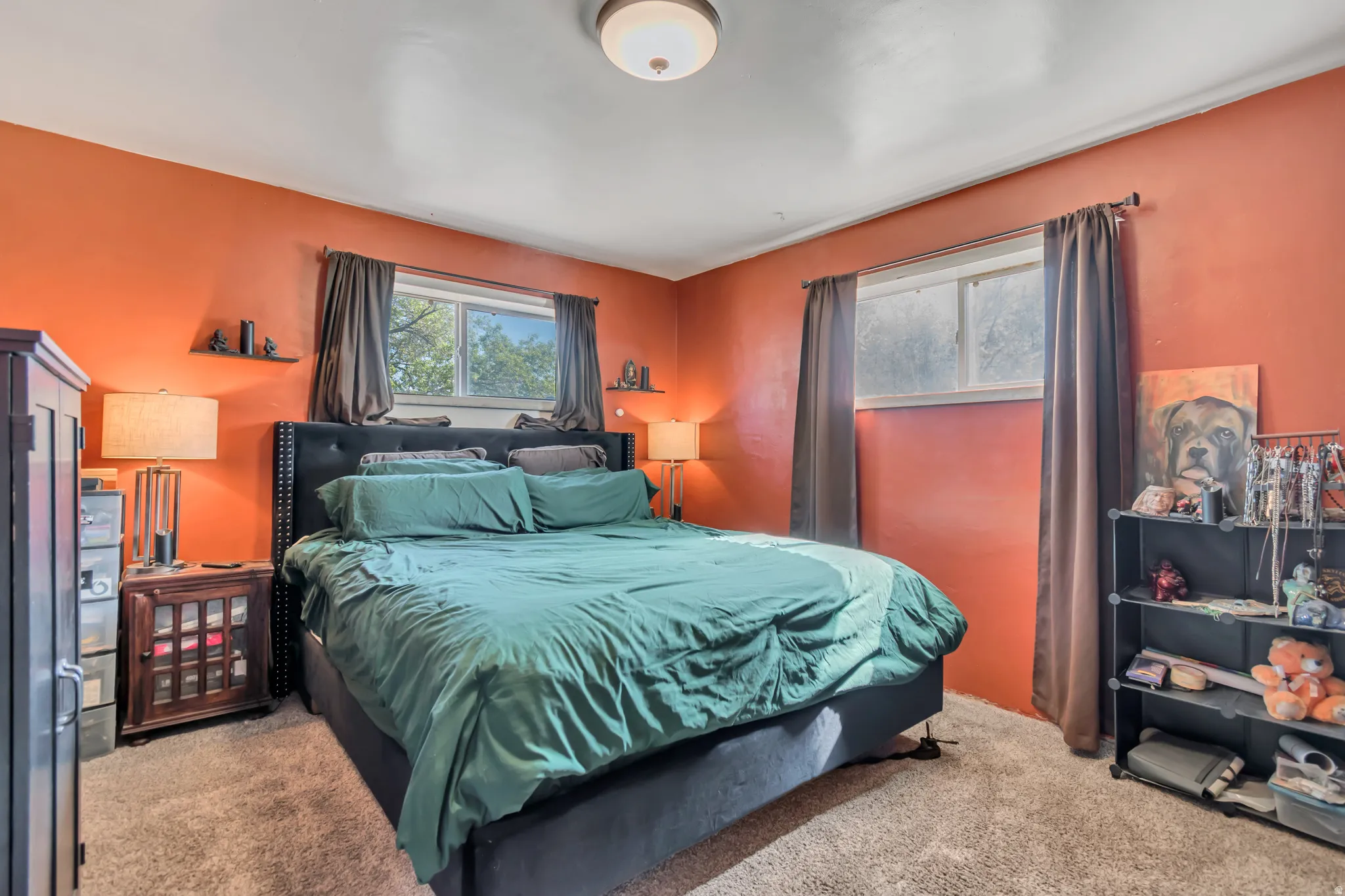 Carpeted bedroom with two windows, a ceiling light fixture, and warm-toned walls