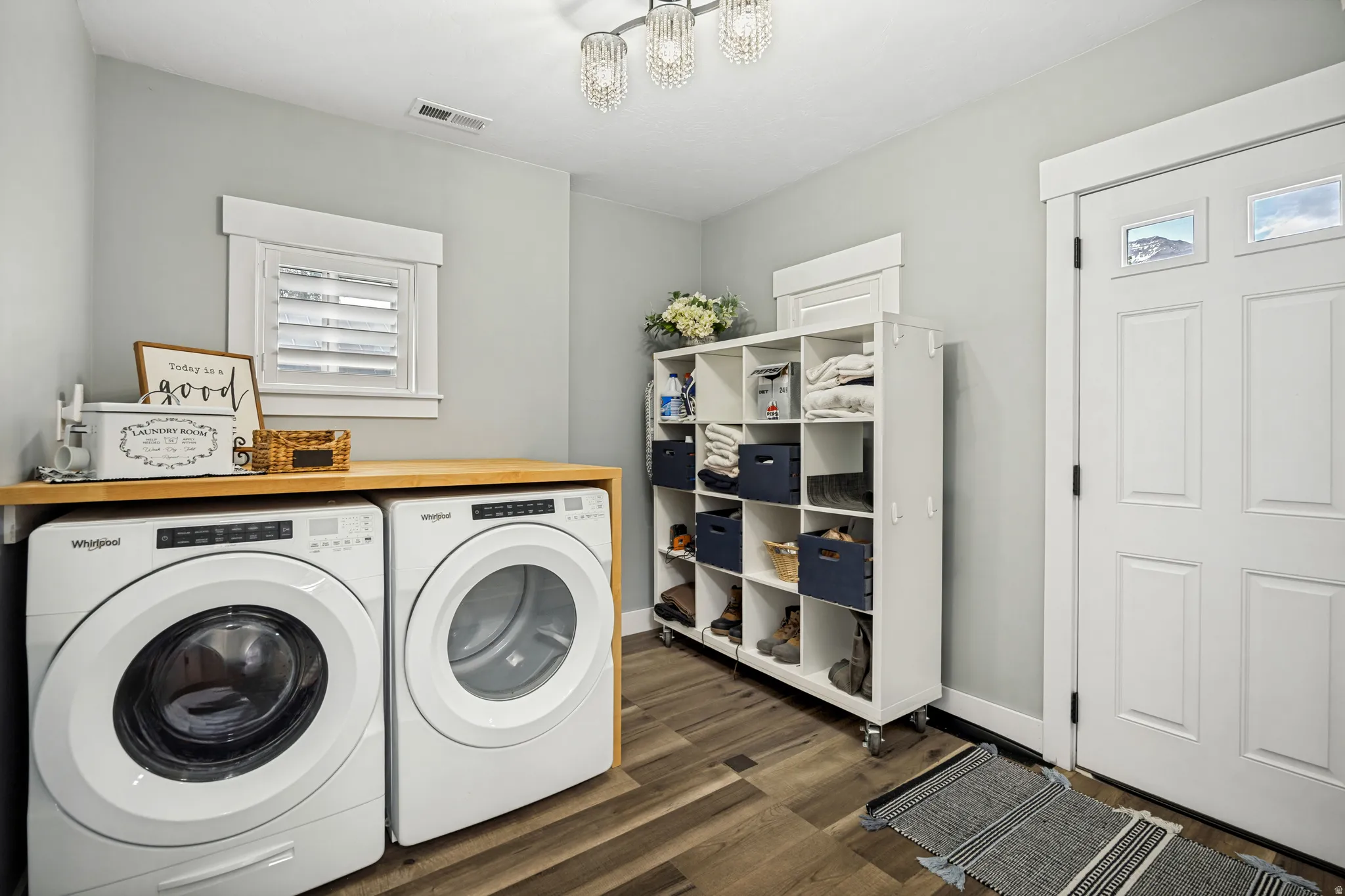 Dedicated laundry area featuring wood-finish flooring and a light wood countertop