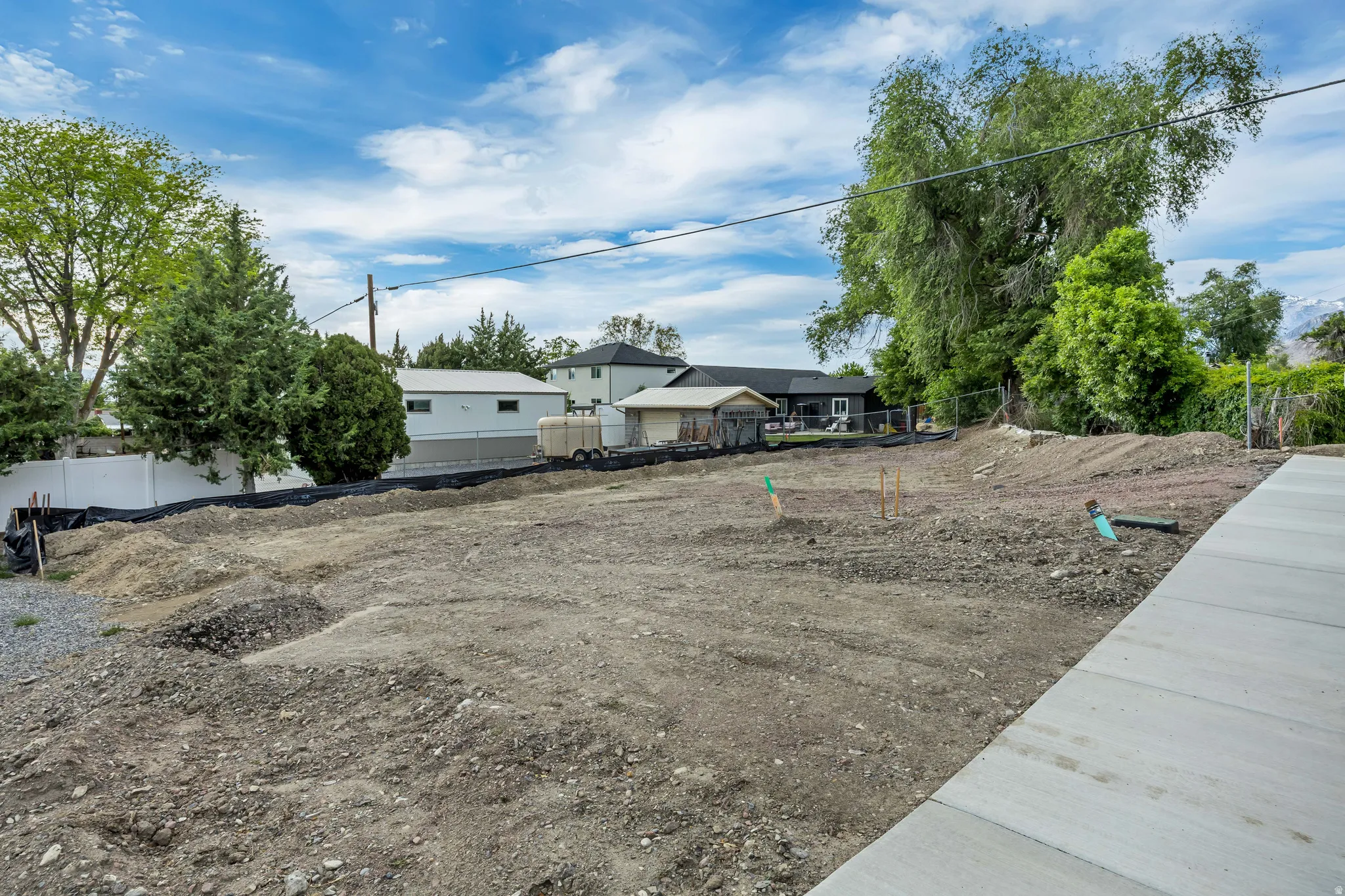 Cleared lot with visible groundwork, perimeter fencing, and concrete paving