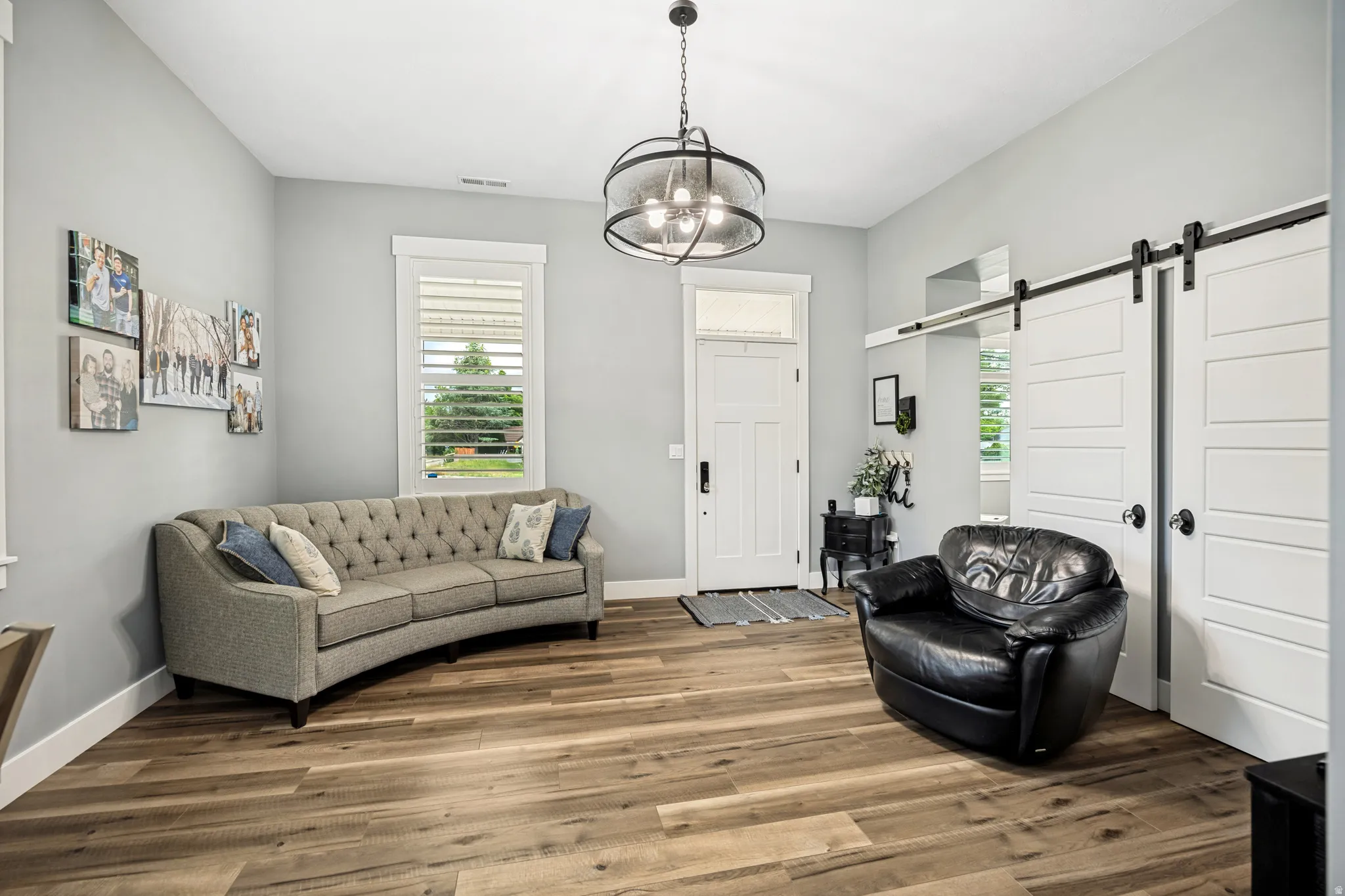 Spacious room with wood-finish flooring, light grey walls, and a contemporary ceiling fixture