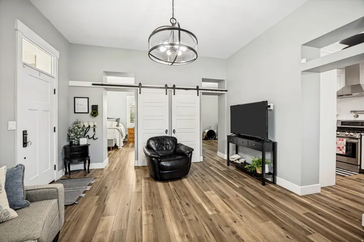 Spacious entry area featuring wood-finish flooring, a modern drum pendant light fixture, and a white front door with transom window