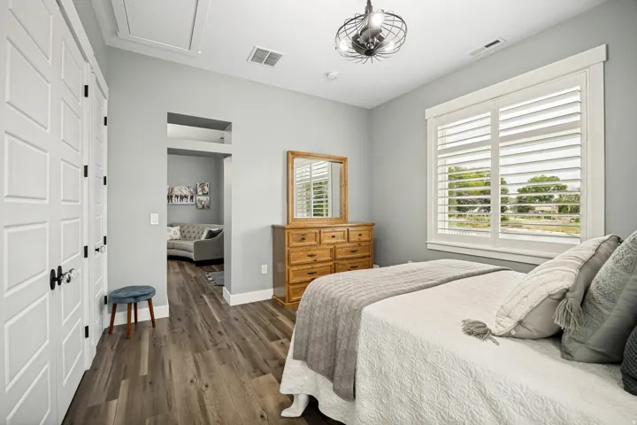 Bedroom featuring wood-finish flooring, plantation shutters, and a modern ceiling fixture