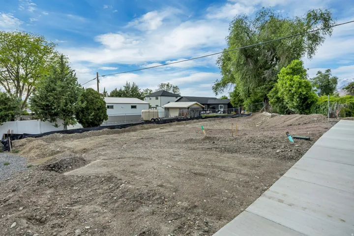 Cleared lot with visible groundwork, perimeter fencing, and concrete paving