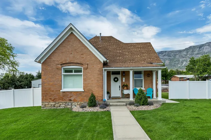 Brick exterior with white trim, a covered front porch, and a pitched shingle roof