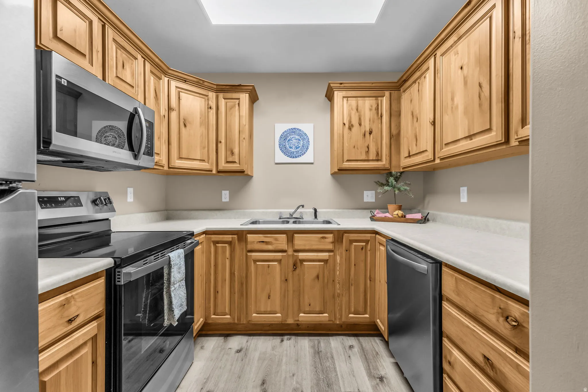 U-shaped kitchen featuring wood cabinetry, light-toned countertops, and wood-finish flooring