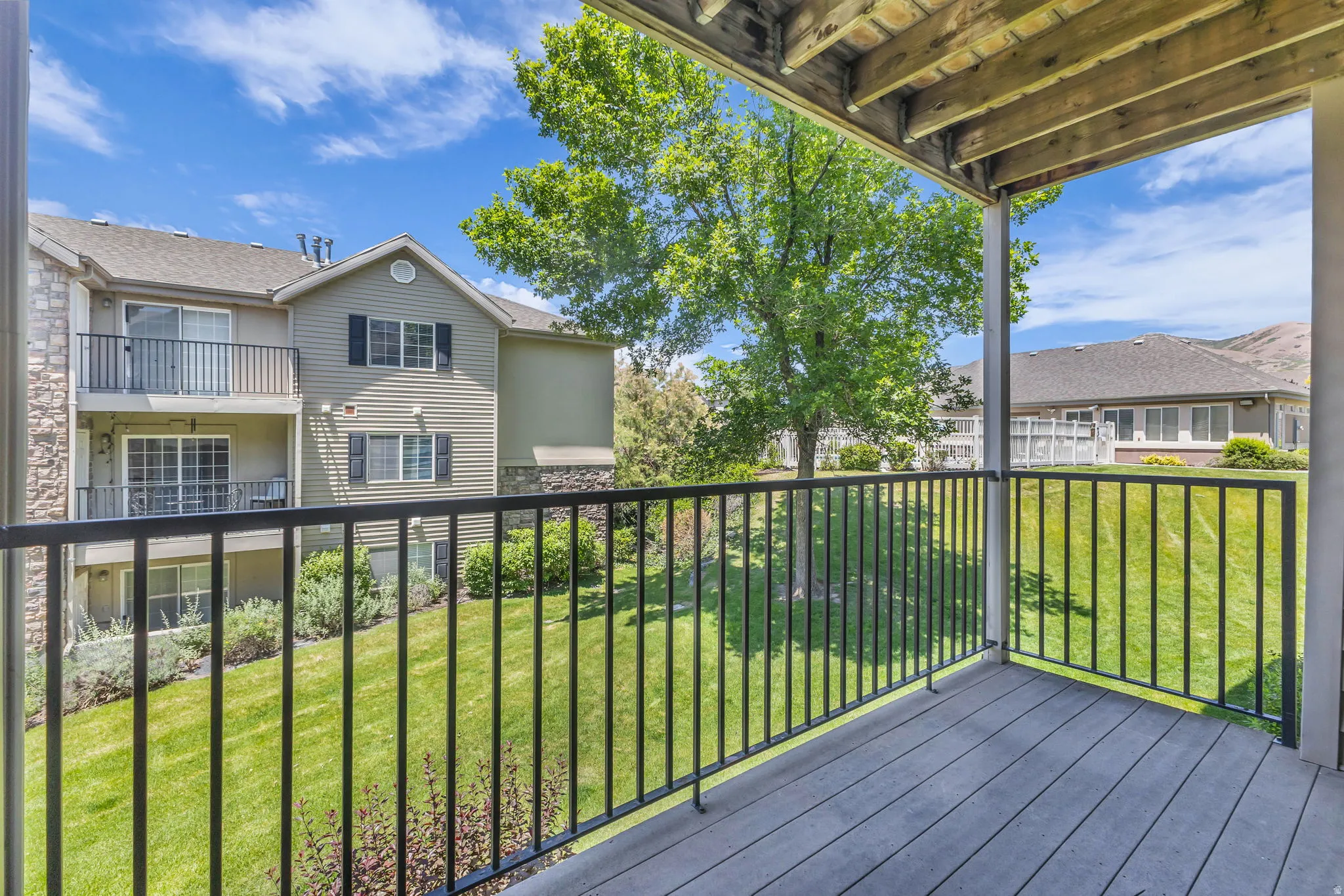 Covered outdoor balcony with wood-finish flooring and a black metal railing