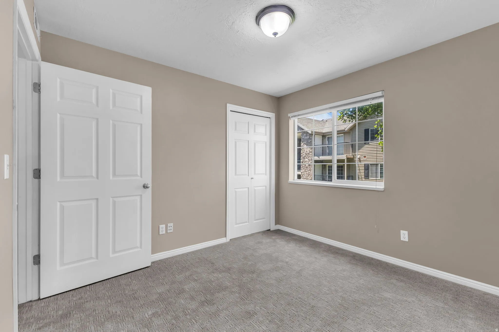 Carpeted room with a large window, neutral wall paint, and white trim