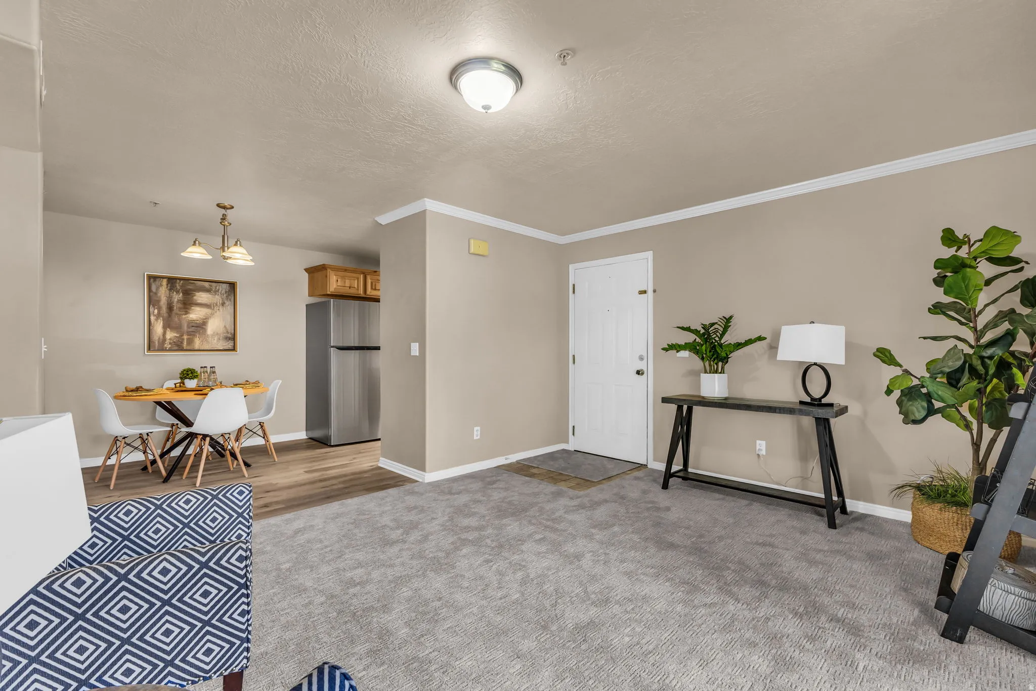 Living area with gray carpeting, crown molding, and a white entry door