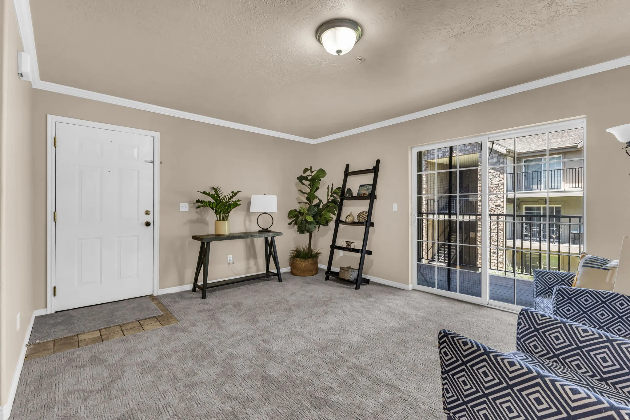 Spacious interior featuring neutral wall tones, crown molding, and a carpeted floor