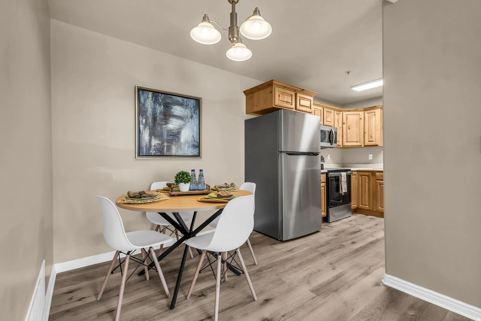 Kitchen and dining area featuring wood-finish flooring, recessed lighting, and a stainless steel refrigerator
