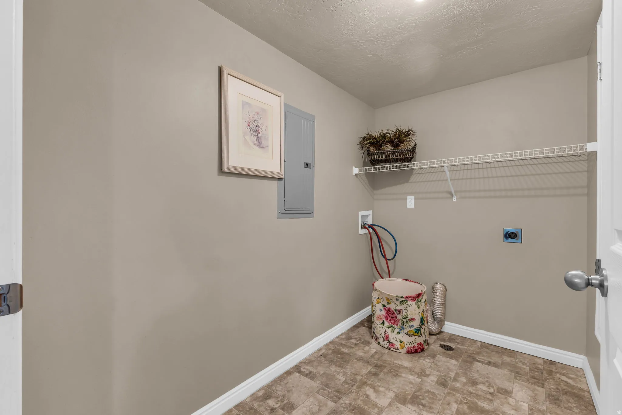 Utility room featuring a wire shelving unit, appliance hookups, and a light-toned flooring
