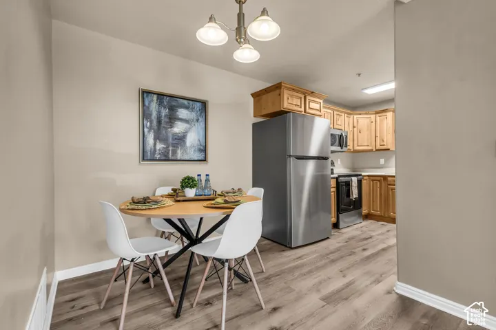 Kitchen and dining area featuring wood-finish flooring, recessed lighting, and a stainless steel refrigerator