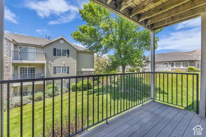 Covered outdoor balcony with wood-finish flooring and a black metal railing