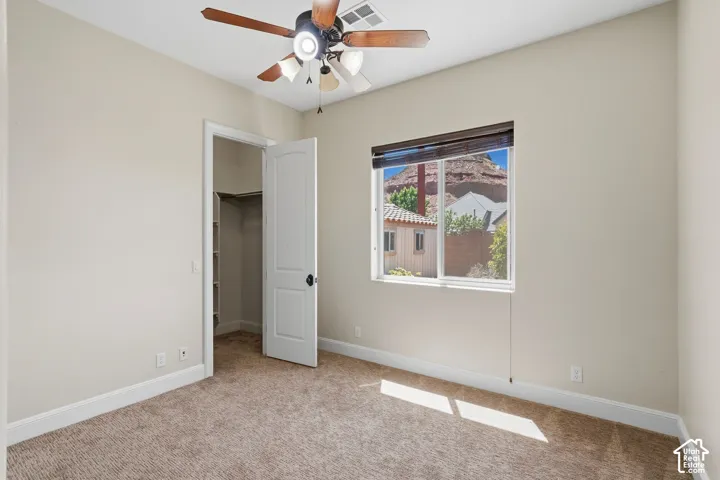 Room featuring a ceiling fan with light fixture, carpeted flooring, and a window with a mountain backdrop