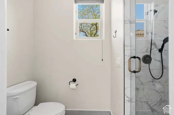 Glass-enclosed shower with marbled tile, bronze hardware, and matte black fixtures