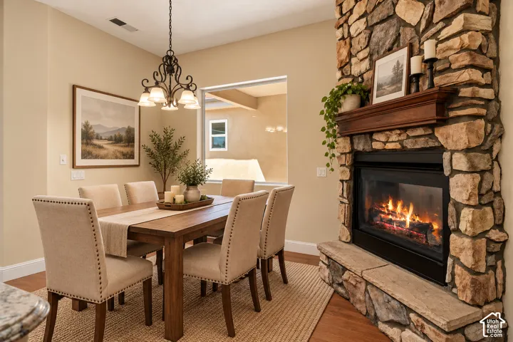 Floor-to-ceiling stone fireplace featuring a prominent wood mantel and raised stone hearth, complemented by a multi-arm metal chandelier and wood-finish flooring