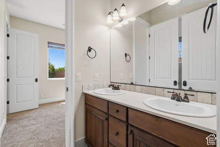 Dual basin vanity with dark wood cabinetry, white countertops, and a full-width mirror