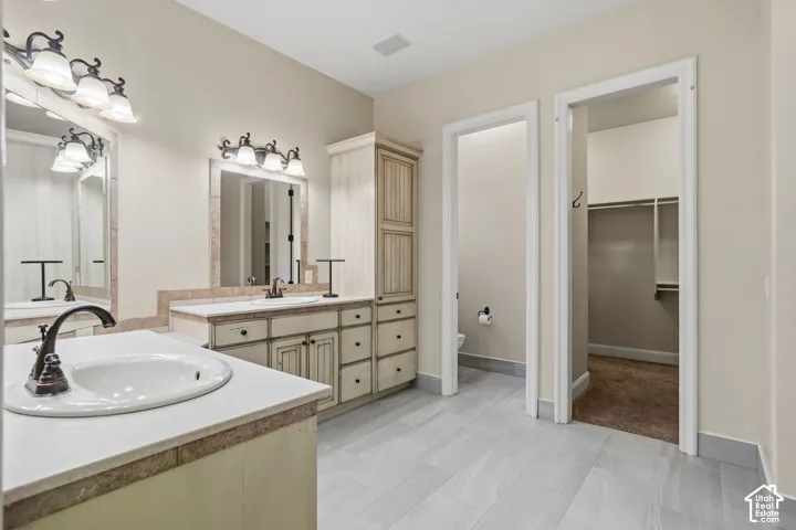 Bathroom featuring dual vanity sinks with bronze fixtures, framed mirrors, and decorative sconce lighting