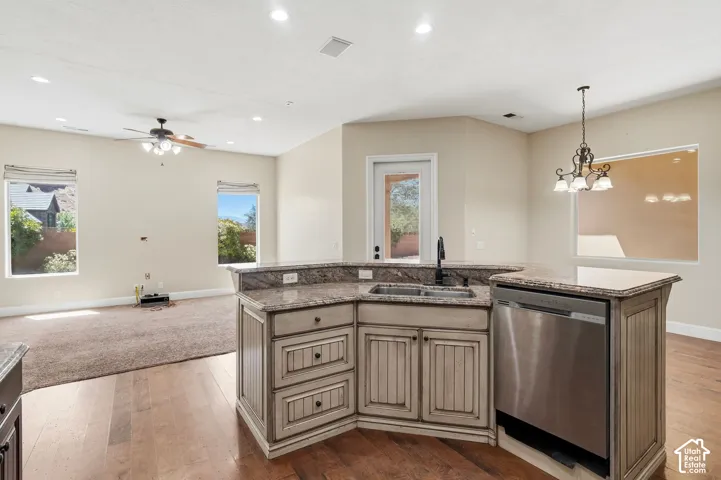 Kitchen island with granite countertops, integrated double basin sink, and stainless steel dishwasher