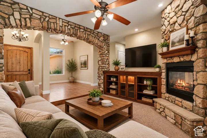 Stacked stone archway, floor-to-ceiling stone fireplace, built-in wooden cabinetry, wood-finish flooring, and multi-blade ceiling fan
