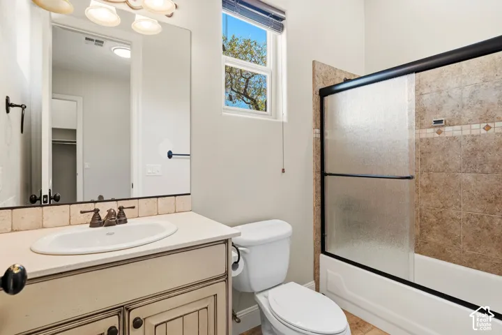 Bathroom featuring a vanity with a white countertop and oval undermount sink, bronze-finish faucet, and distressed cream cabinetry