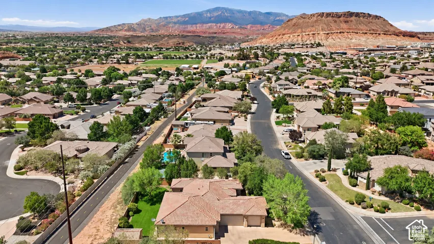 Aerial perspective featuring mountain and mesa landscapes, multi-pitch rooflines, attached multi-car garage, and established residential landscaping