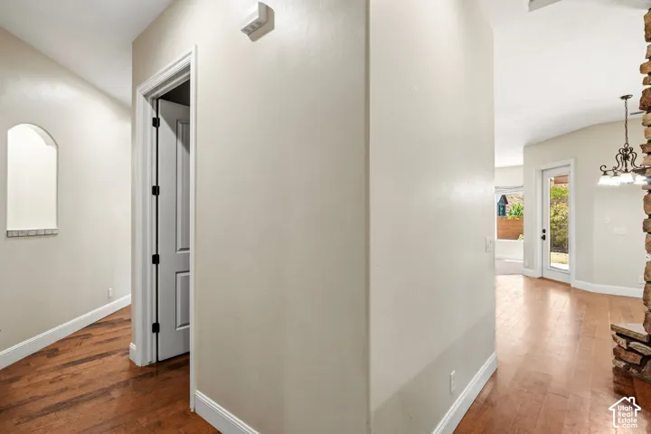 Wood-finish flooring, recessed wall niche with stone detailing, stone-accented fireplace surround, and multi-pane glass door