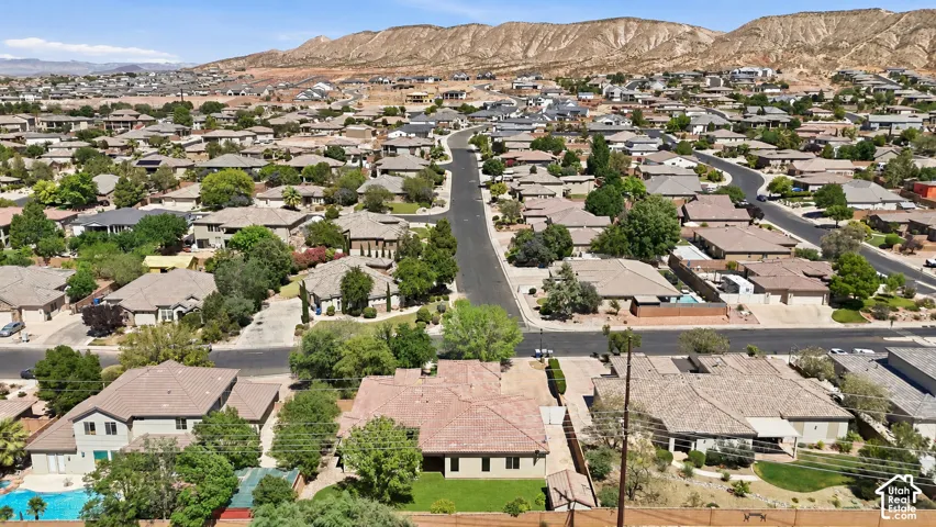 Aerial perspective featuring a stucco residence with a tiled roof, a lawn area, and a backdrop of mountain ridges